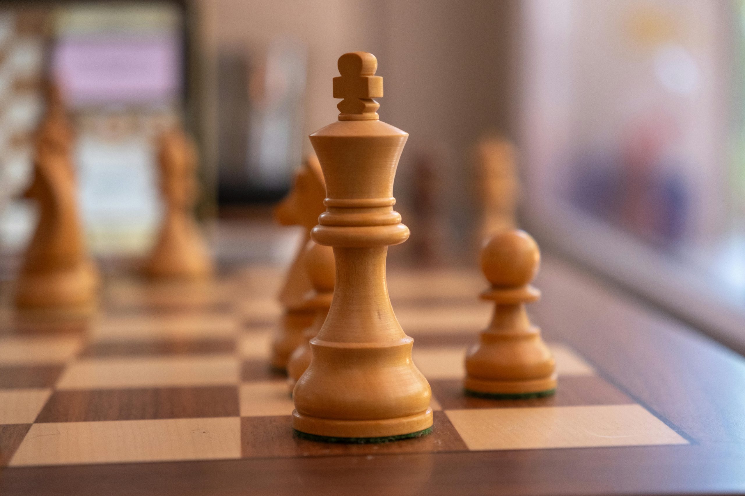 Detailed shot of chess pieces with selective focus, featuring a queen and pawn on a wooden board.
