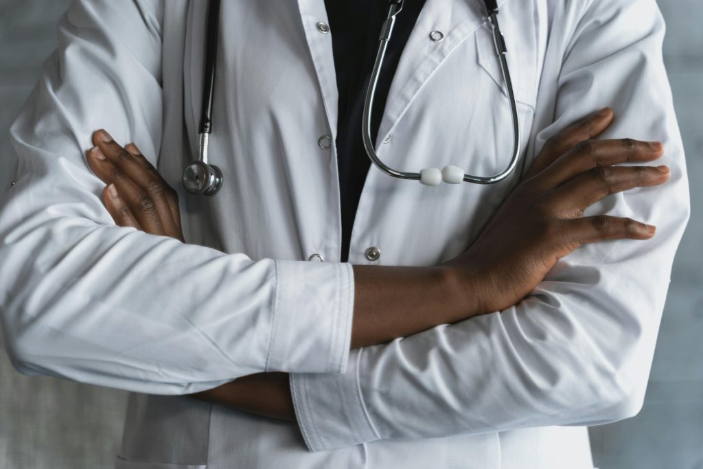 Close-up of a confident doctor in a lab coat standing with crossed arms and stethoscope.