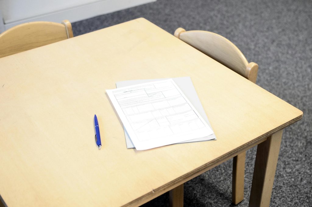 Empty classroom desk with paperwork and pen, ideal for educational themes.
