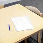 Empty classroom desk with paperwork and pen, ideal for educational themes.