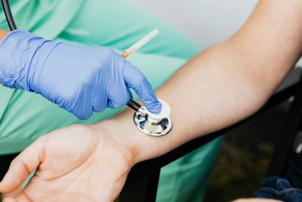 Healthcare professional using a stethoscope on patient's wrist during a medical exam.